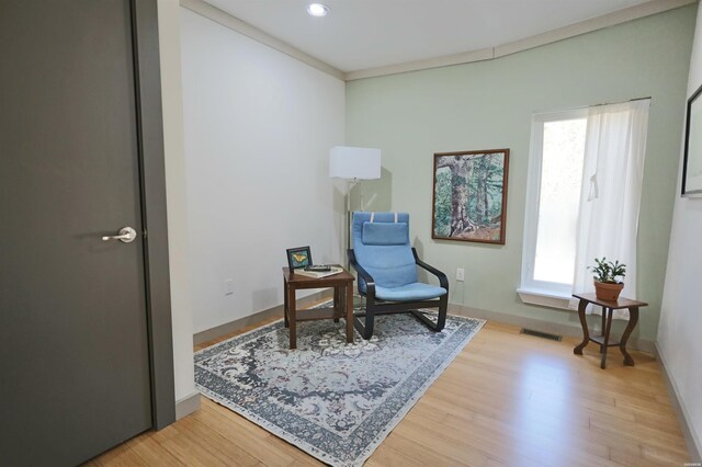 living area featuring light wood-style flooring, visible vents, ornamental molding, and recessed lighting