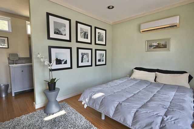 bedroom featuring crown molding, baseboards, wood finished floors, and a wall mounted air conditioner