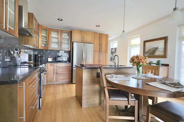 kitchen with appliances with stainless steel finishes, brown cabinetry, glass insert cabinets, and pendant lighting