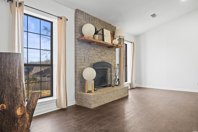 unfurnished living room with dark wood-style flooring, a fireplace, visible vents, and baseboards