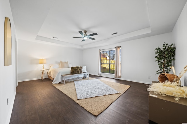 bedroom with dark wood-type flooring, a raised ceiling, and visible vents