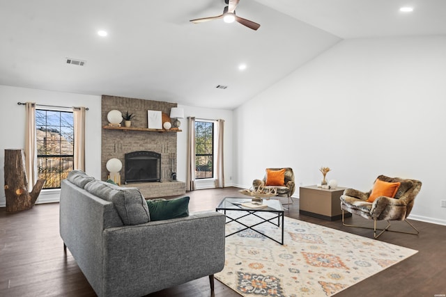 living area featuring plenty of natural light, vaulted ceiling, a fireplace, and visible vents