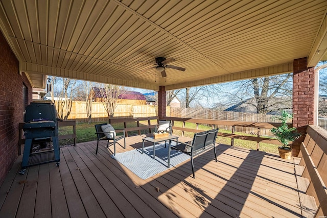 wooden terrace featuring ceiling fan, outdoor lounge area, a fenced backyard, and a grill