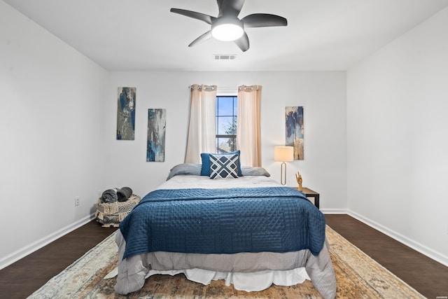 bedroom with a ceiling fan, visible vents, baseboards, and wood finished floors