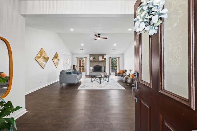 living area featuring a large fireplace, baseboards, vaulted ceiling, and dark wood-style flooring