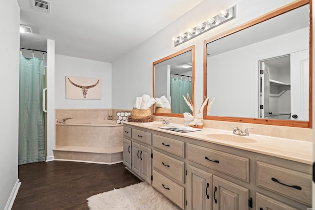 full bath featuring double vanity, visible vents, wood finished floors, a sink, and a bath