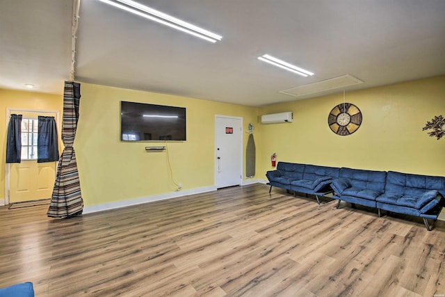 living room with attic access, baseboards, wood finished floors, and a wall mounted air conditioner