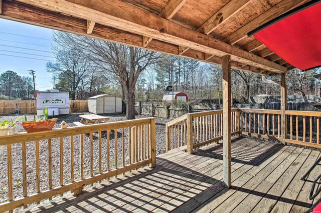 wooden terrace with a storage shed, an outbuilding, and a fenced backyard