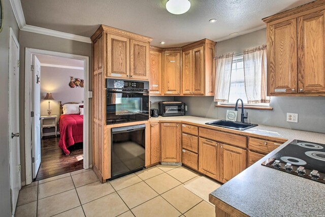 kitchen featuring black appliances, light countertops, a sink, and brown cabinetry