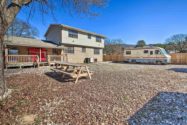 back of house featuring brick siding, fence, and a wooden deck