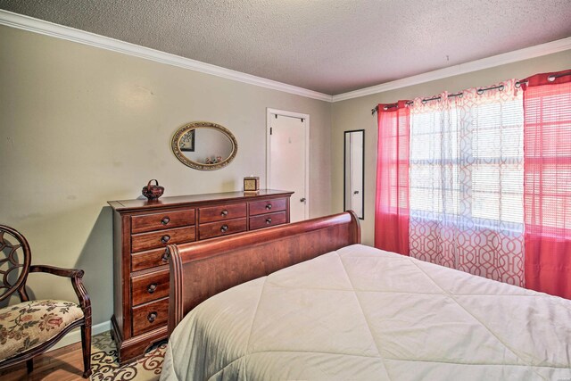 bedroom with ornamental molding, a textured ceiling, and wood finished floors