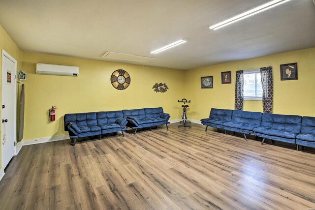 living area featuring a wall mounted AC, wood finished floors, attic access, and baseboards