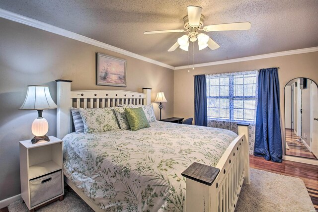 bedroom with dark wood-type flooring, crown molding, a textured ceiling, and a ceiling fan