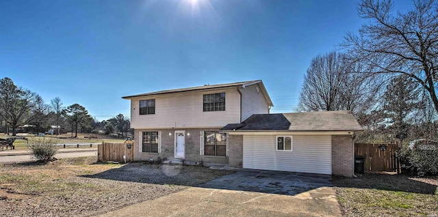 view of front of property with brick siding, fence, and driveway