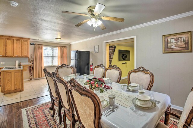 dining area with a textured ceiling, ceiling fan, light wood-style flooring, and crown molding