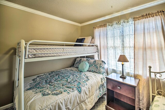 bedroom with a textured ceiling, multiple windows, and crown molding