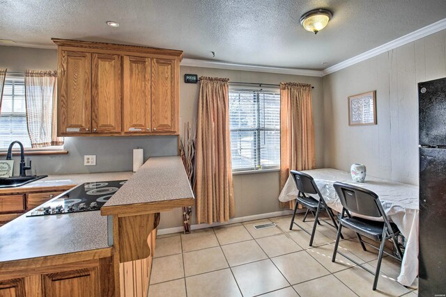 kitchen with brown cabinets, light countertops, crown molding, black appliances, and a sink