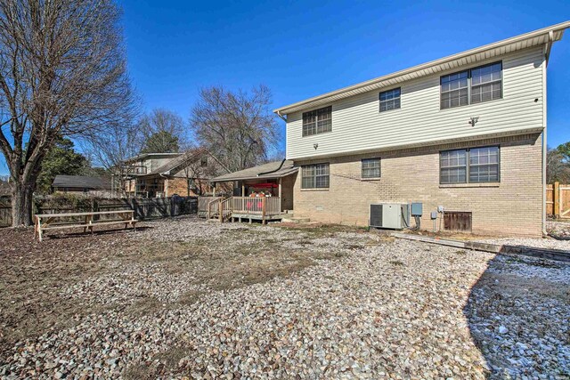 rear view of house with brick siding, fence, a wooden deck, and central air condition unit