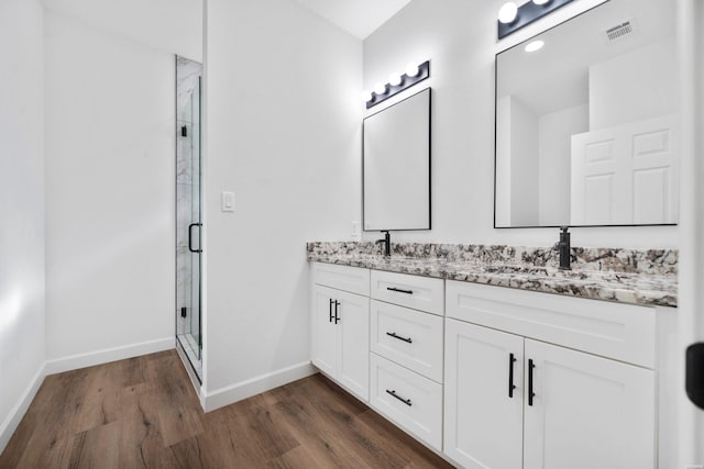 bathroom featuring visible vents, a shower stall, baseboards, and wood finished floors