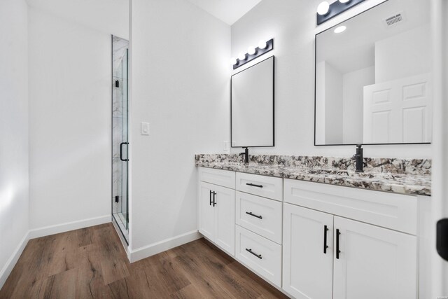 bathroom featuring visible vents, a shower stall, baseboards, and wood finished floors