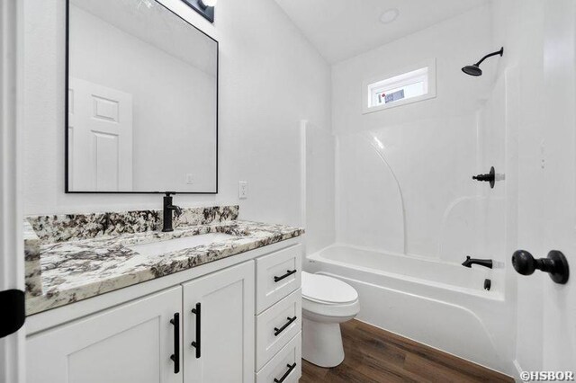 full bath with toilet, shower / washtub combination, wood finished floors, and vanity