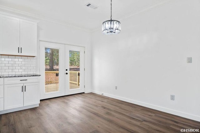 unfurnished dining area with french doors, visible vents, ornamental molding, dark wood-type flooring, and baseboards