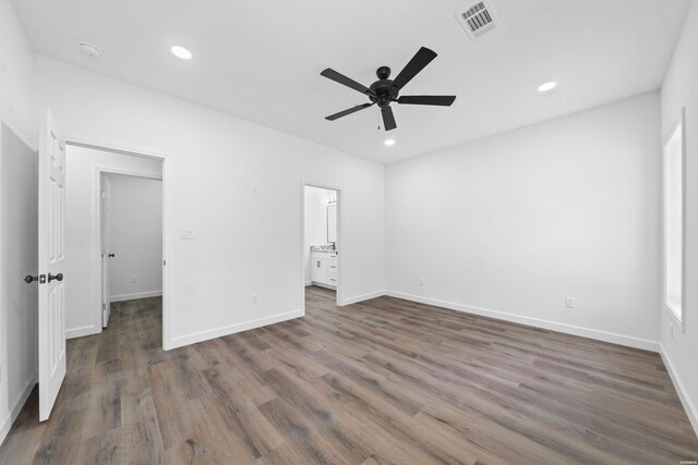 unfurnished bedroom featuring dark wood-style floors, ensuite bath, baseboards, and recessed lighting