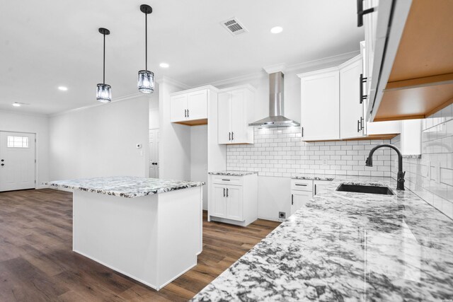 kitchen with visible vents, wall chimney exhaust hood, a sink, and white cabinetry