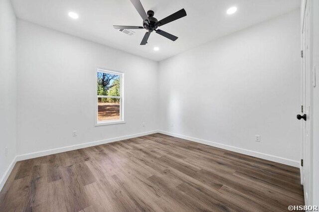 spare room featuring recessed lighting, wood finished floors, and baseboards