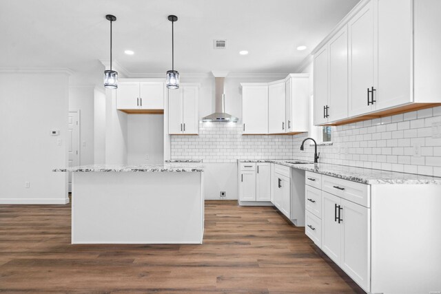 kitchen with hanging light fixtures, wall chimney exhaust hood, white cabinetry, and a center island