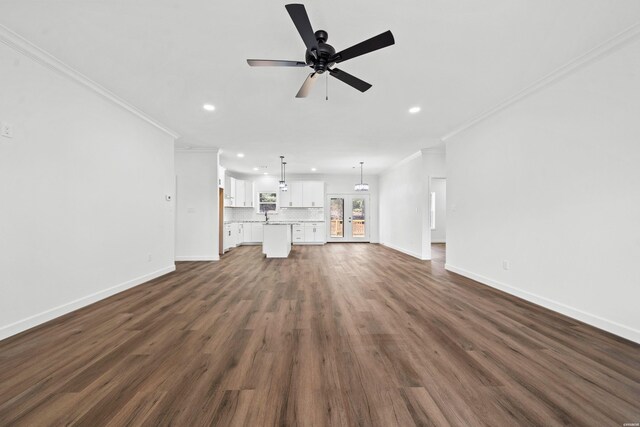 unfurnished living room featuring baseboards, ornamental molding, dark wood finished floors, and recessed lighting