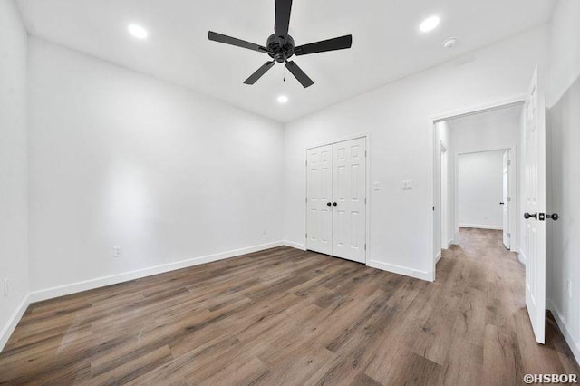 unfurnished bedroom with recessed lighting, dark wood-style flooring, a ceiling fan, baseboards, and a closet