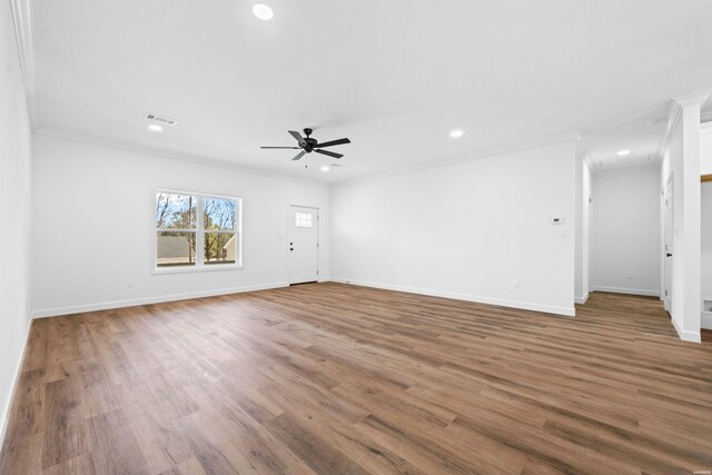 unfurnished living room with baseboards, visible vents, wood finished floors, crown molding, and recessed lighting