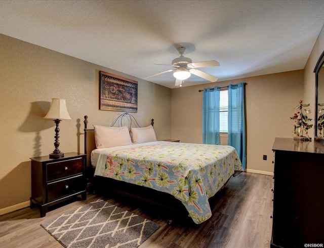 bedroom with ceiling fan, wood finished floors, and baseboards