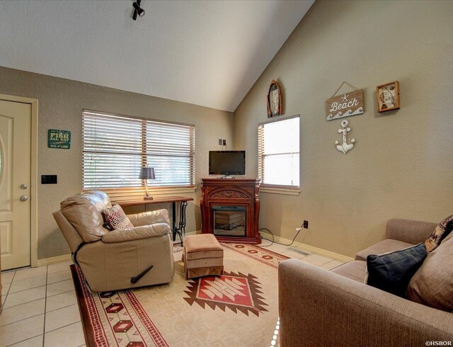 living room with lofted ceiling, a glass covered fireplace, baseboards, and light tile patterned floors