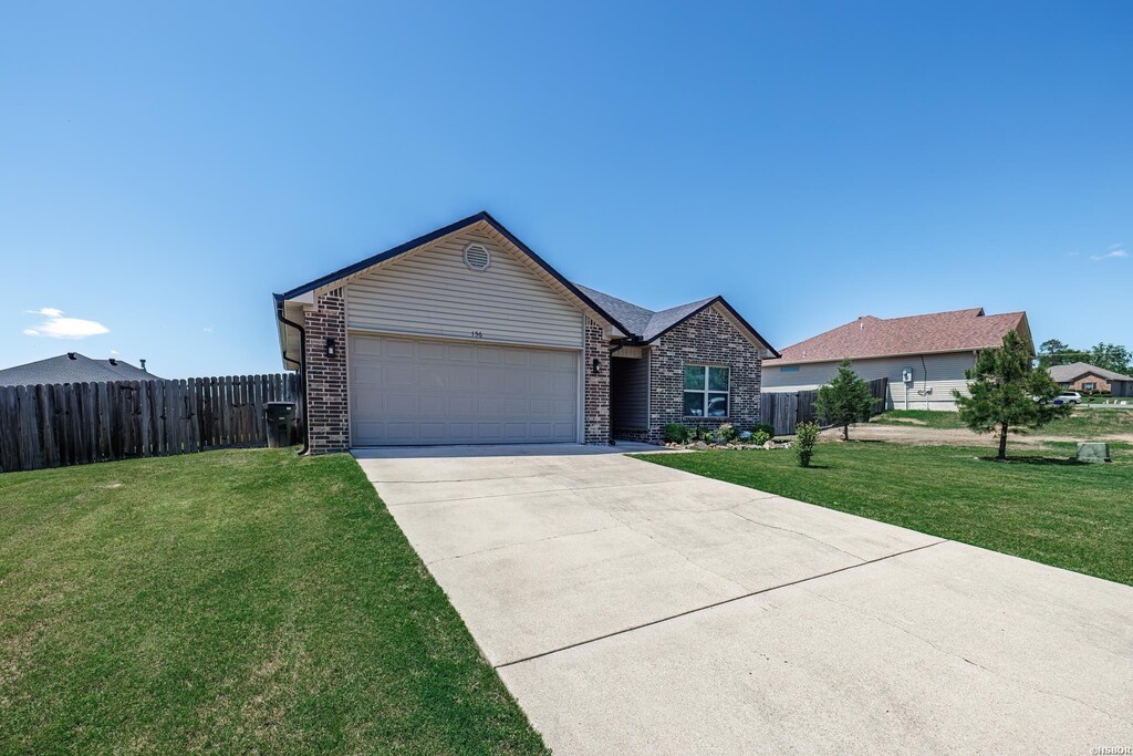 single story home with brick siding, an attached garage, fence, and a front yard