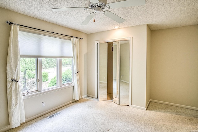 unfurnished bedroom with carpet flooring, a textured ceiling, visible vents, and a closet
