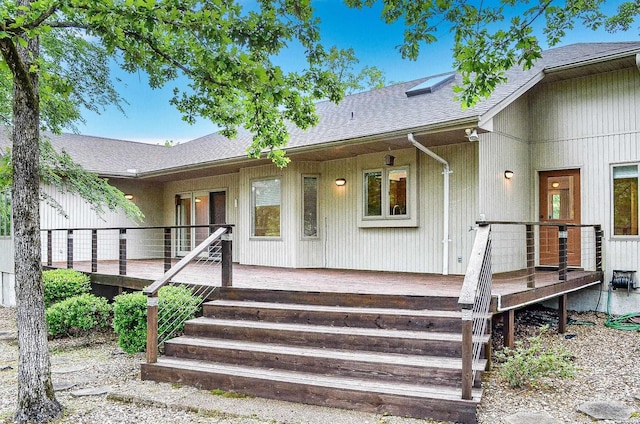 entrance to property featuring roof with shingles and a deck