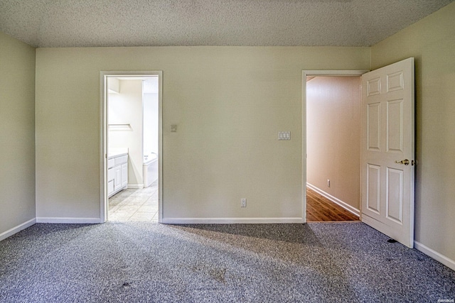 empty room with baseboards, a textured ceiling, and carpet