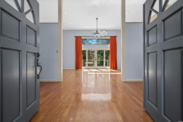 foyer featuring recessed lighting, a towering ceiling, baseboards, and wood finished floors