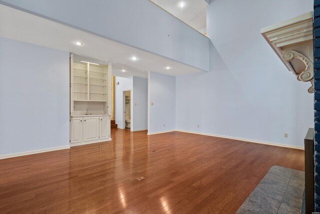 unfurnished living room featuring recessed lighting, wood finished floors, and baseboards