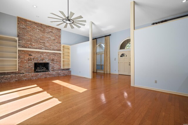 unfurnished living room with built in features, baseboards, ceiling fan, wood finished floors, and a fireplace