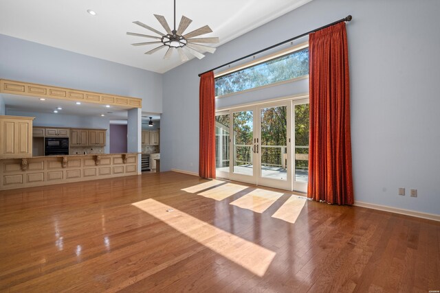 unfurnished living room featuring french doors, plenty of natural light, a towering ceiling, and wood finished floors