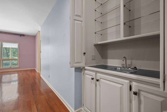 bar with baseboards, a sink, and wood finished floors