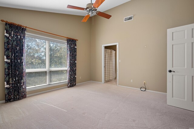 carpeted empty room with a high ceiling, visible vents, and baseboards