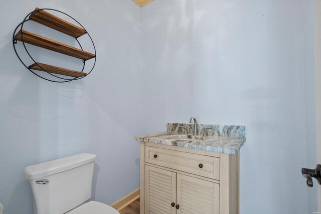 bathroom featuring toilet, baseboards, and vanity