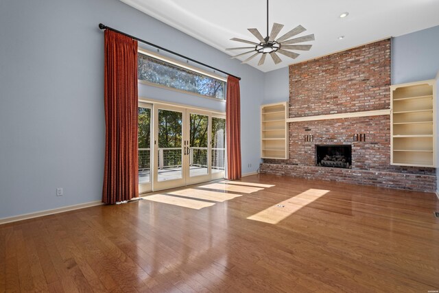 unfurnished living room featuring french doors, a fireplace, hardwood / wood-style floors, and ceiling fan