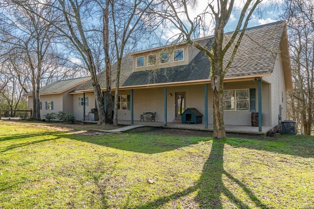 view of front of house with a front yard, a patio area, and roof with shingles