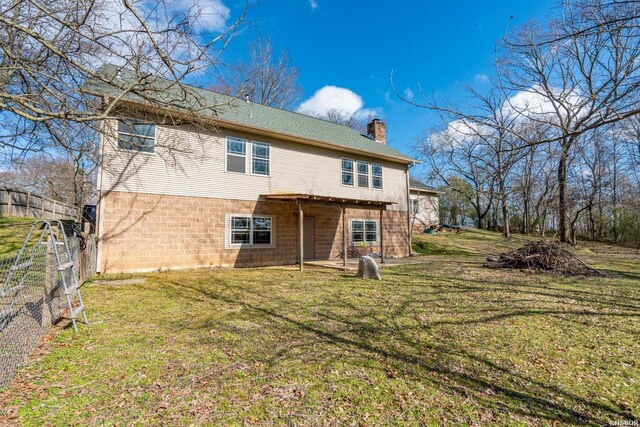 rear view of house featuring a yard, a chimney, and a fenced backyard