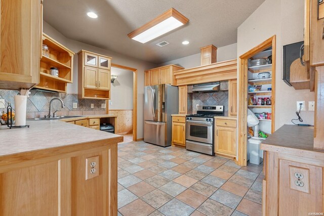 kitchen featuring range hood, open shelves, stainless steel appliances, glass insert cabinets, and a sink